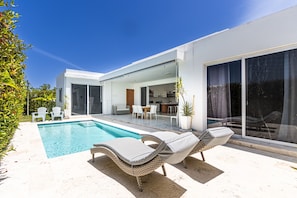 A modern house with a swimming pool, outdoor seating, and large sliding glass doors. - Family Villa With Private Pool in Sosua Ocean Village (Sosúa)