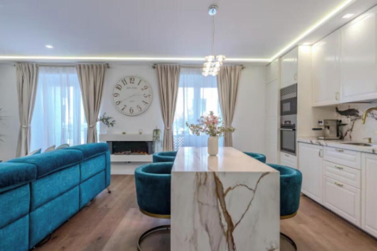 A modern living room with a sofa, a marble coffee table, and a large wall clock.