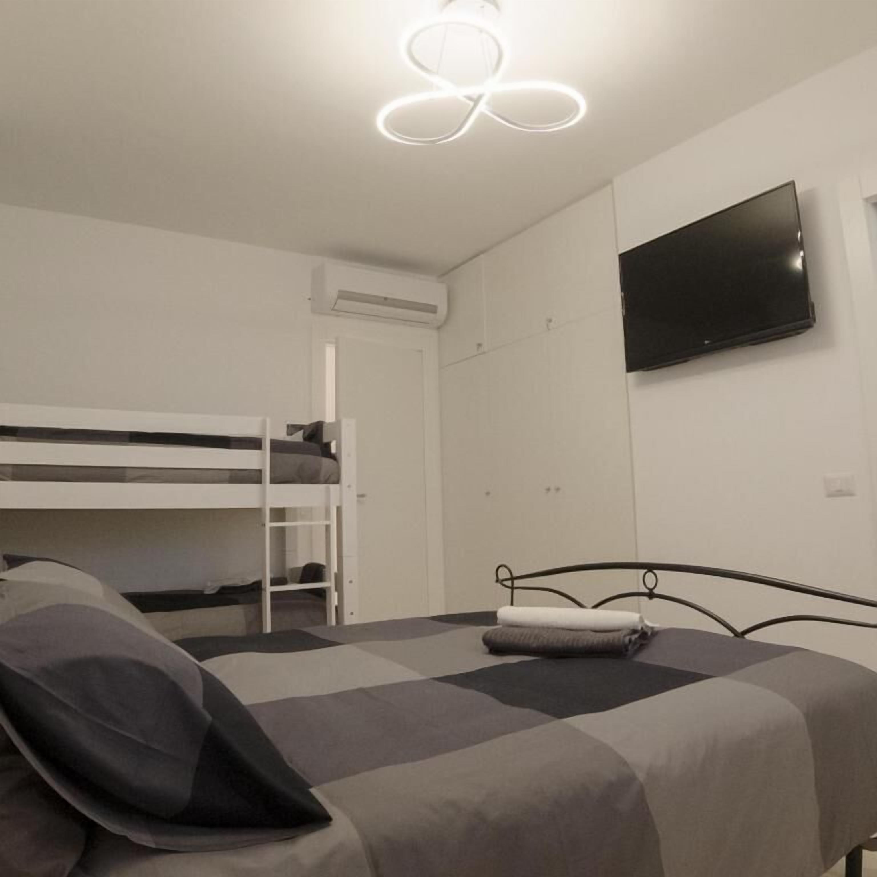 A room with a bunk bed, a flat-screen TV, and a ceiling light fixture.