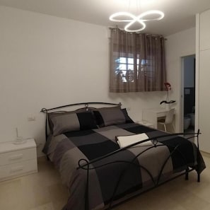 Une chambre à coucher avec un lit, une table de chevet et une fenêtre avec des rideaux.