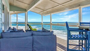 En inglasad veranda med utsikt över havet, en blå stol och en soffa med kuddar.
