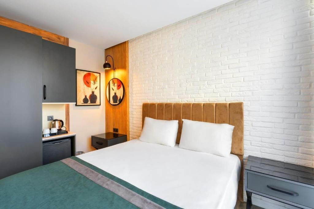 Una habitación de hotel con cama, mesita de noche, cómoda, cafetera y una obra de arte colgada en la pared.
