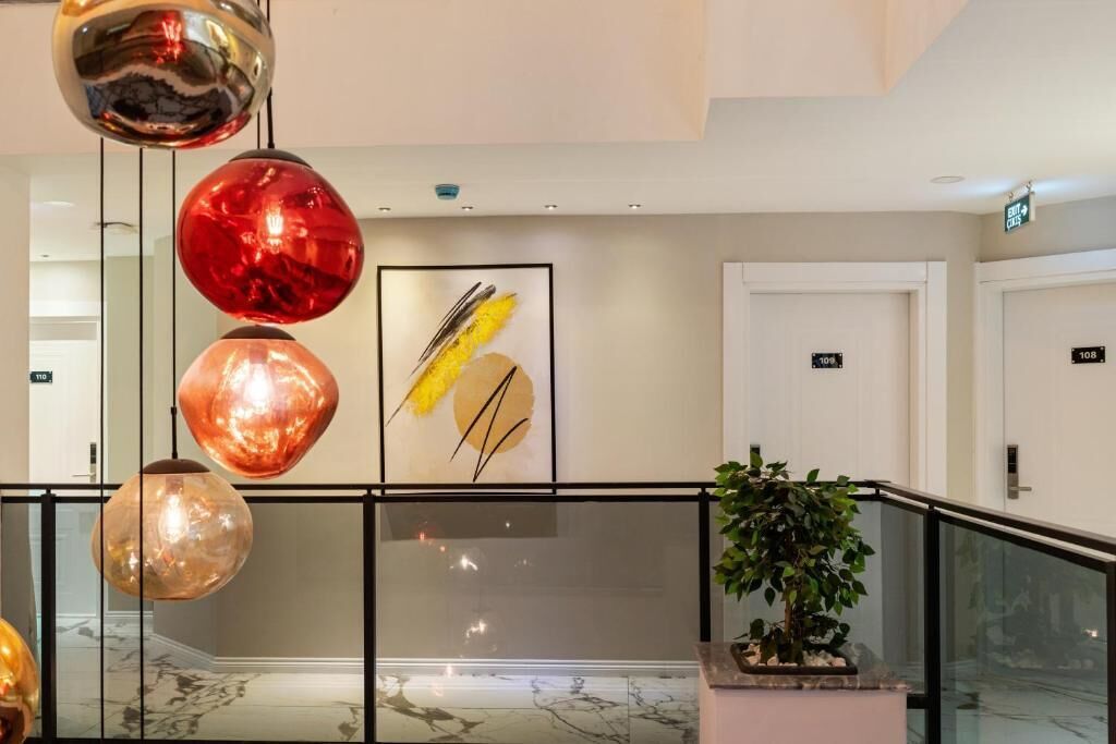 A modern lobby with hanging spherical lights, a framed artwork, a potted plant, and a marble floor.