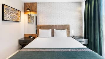 A hotel room with a brick-patterned wall, a bed with a headboard, a bedside table, a lamp, and a window with curtains.