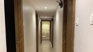 Pasillo de hotel con puertas de madera, piso de baldosas y una lámpara en el techo.