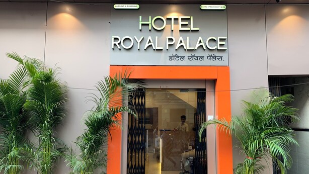 La entrada del Hotel Royal Palace con un diseño moderno, destacando un letrero llamativo y plantas en macetas.