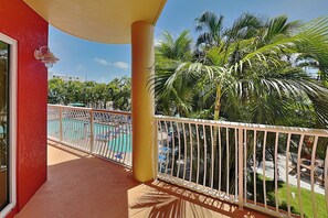 A balcony with a view of a pool and palm trees. - Crystal Palms 207 | Modern + Resort Amenities (Treasure Island)
