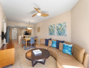A modern living room with a sofa, coffee table, and dining area. - Crystal Palms 207 | Modern + Resort Amenities (Treasure Island)