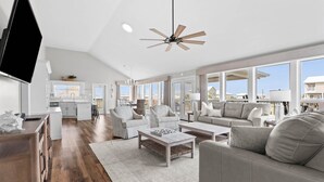 A spacious living area with a ceiling fan, large windows, a kitchen, and a dining area. - Boat Friendly Canal Retreat | Private Pool + Private Pier (Dauphin Island)