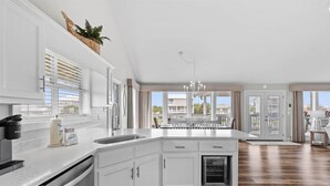 A spacious kitchen with white cabinetry, a built-in dishwasher, and a large island. - Boat Friendly Canal Retreat | Private Pool + Private Pier (Dauphin Island)