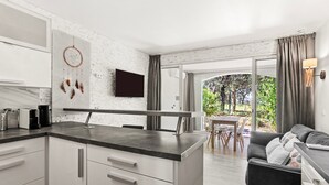 A modern kitchen with white cabinets, a marble backsplash, and a dreamcatcher on the wall. - Air-conditioned Apartment with Pool and Tennis in Les Restanques, Grimaud (Grimaud)