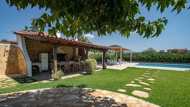 A stone patio leading to a covered outdoor dining area with a pool in the background. - Poolside Paradise Dilesi by ΜΡS (Πλάκα Δήλεσι)