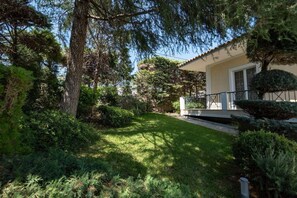 Ein Wohnhaus mit gepflegtem Rasen, reifen Bäumen und einem zweistöckigen Gebäude mit Balkon.