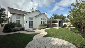 Une maison à deux étages avec un patio couvert, une pelouse et une allée pavée.