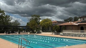 Une piscine à l’eau claire, entourée d’une terrasse aménagée avec des chaises longues et une pergola.