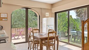 A dining area with a table and chairs, a refrigerator, and a view of the outdoors.
