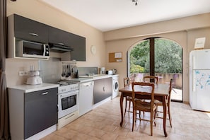 A modern kitchen with a dining area, a view through a large window, and a clock on the wall. - Welcome to "Gite la Loge" in St Aignan (Saint-Aignan)