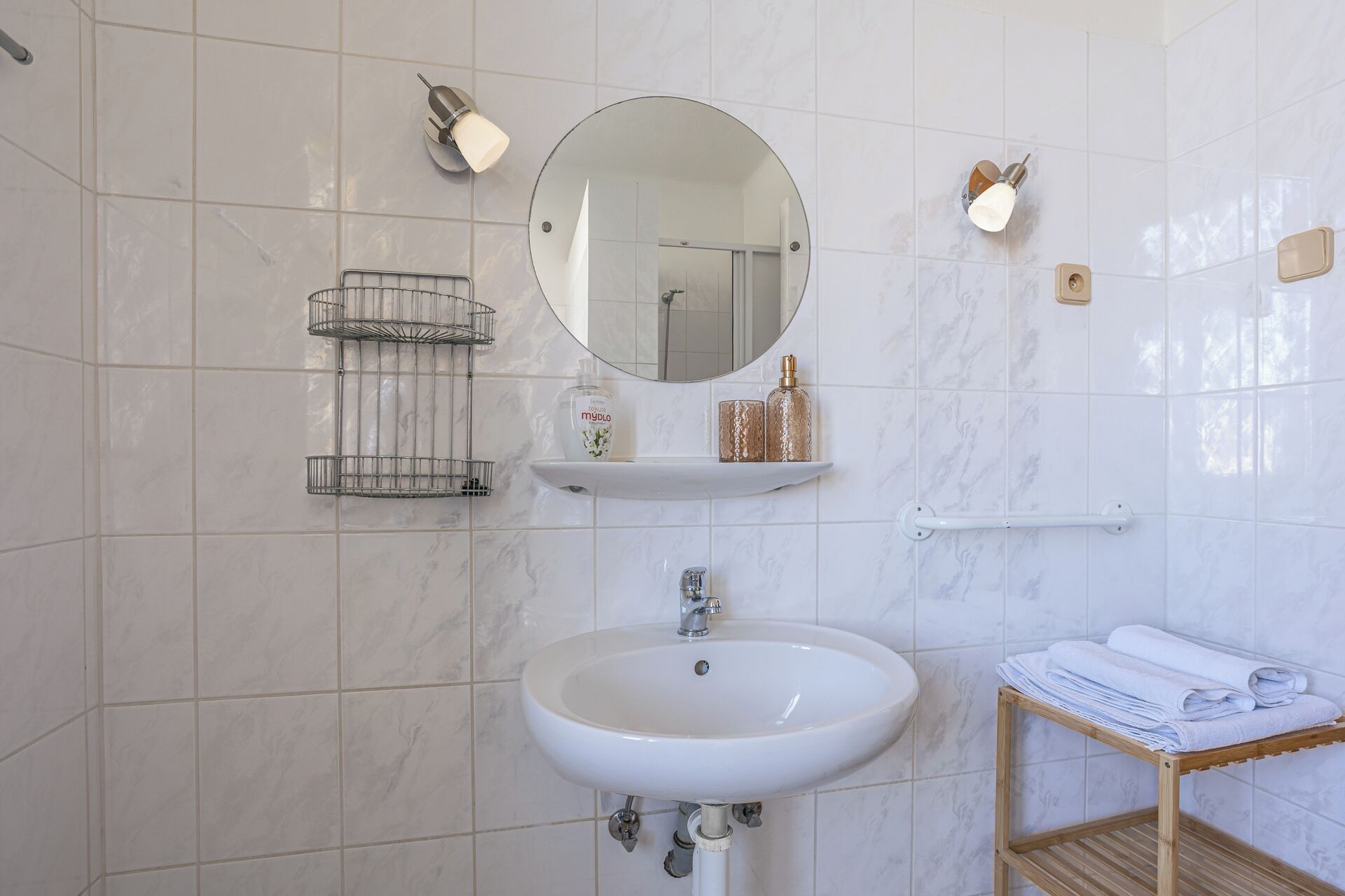 A bathroom with a white sink, mirror, and towel rack.
