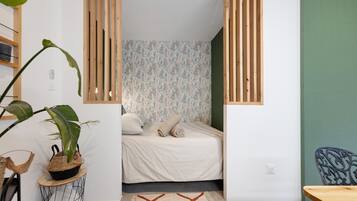 A small, cozy bedroom with a bed, a green wall, and a wooden partition.
