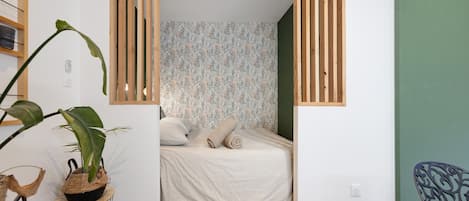 A small, cozy bedroom with a bed, a green wall, and a wooden partition.