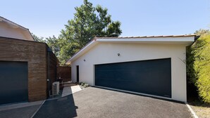 Un garage moderne, pouvant accueillir deux voitures, avec une allée en gravier et une clôture en bois.