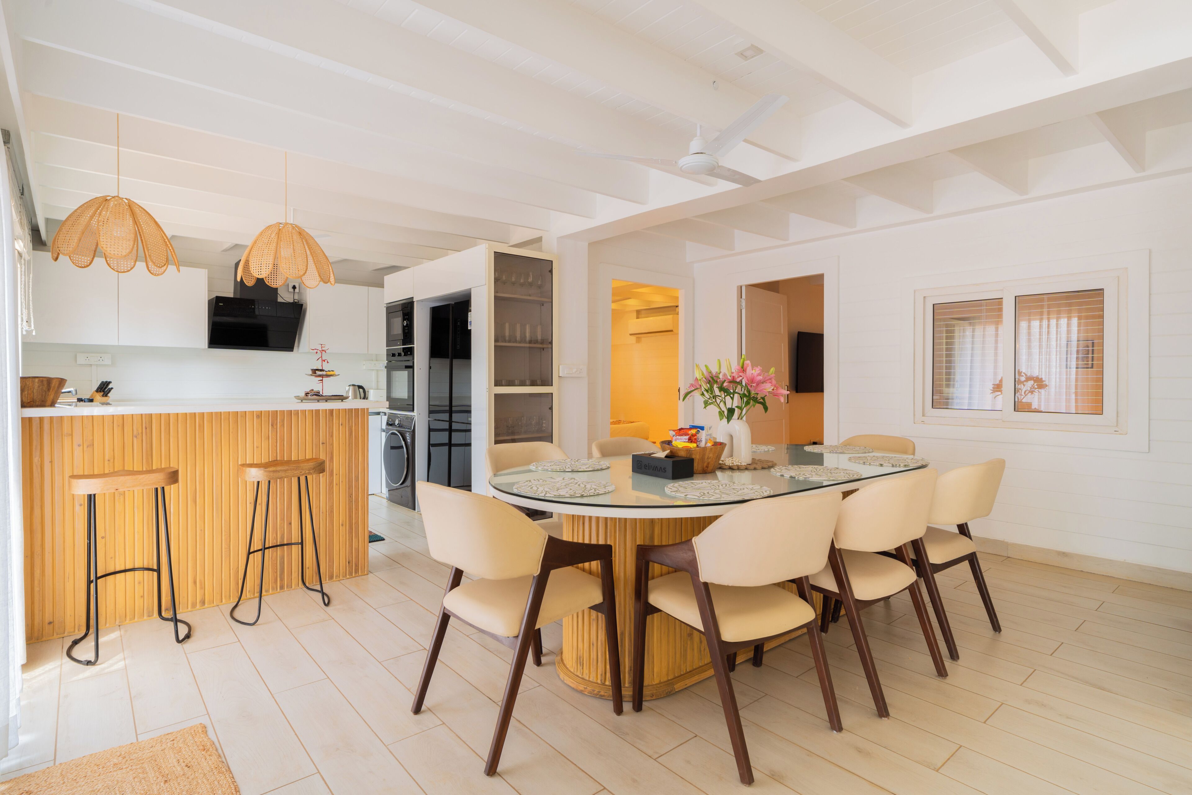 A modern kitchen with white cabinets, a central island with stools, and pendant lighting.