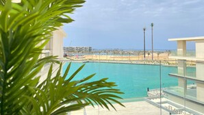 A pool with a clear view of the beach and palm trees in the background. - 2 BR Sapphire 405 in Marassi North Coast (El Alamein)