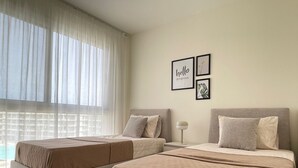 A hotel room with two beds, a large window with sheer curtains, and wall art. - 2 BR Sapphire 405 in Marassi North Coast (El Alamein)