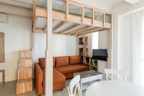 A loft-style room with a built-in bed, a sofa, a TV, and a bookshelf. - Saliceto Studio by Wonderful Italy (Bologna)