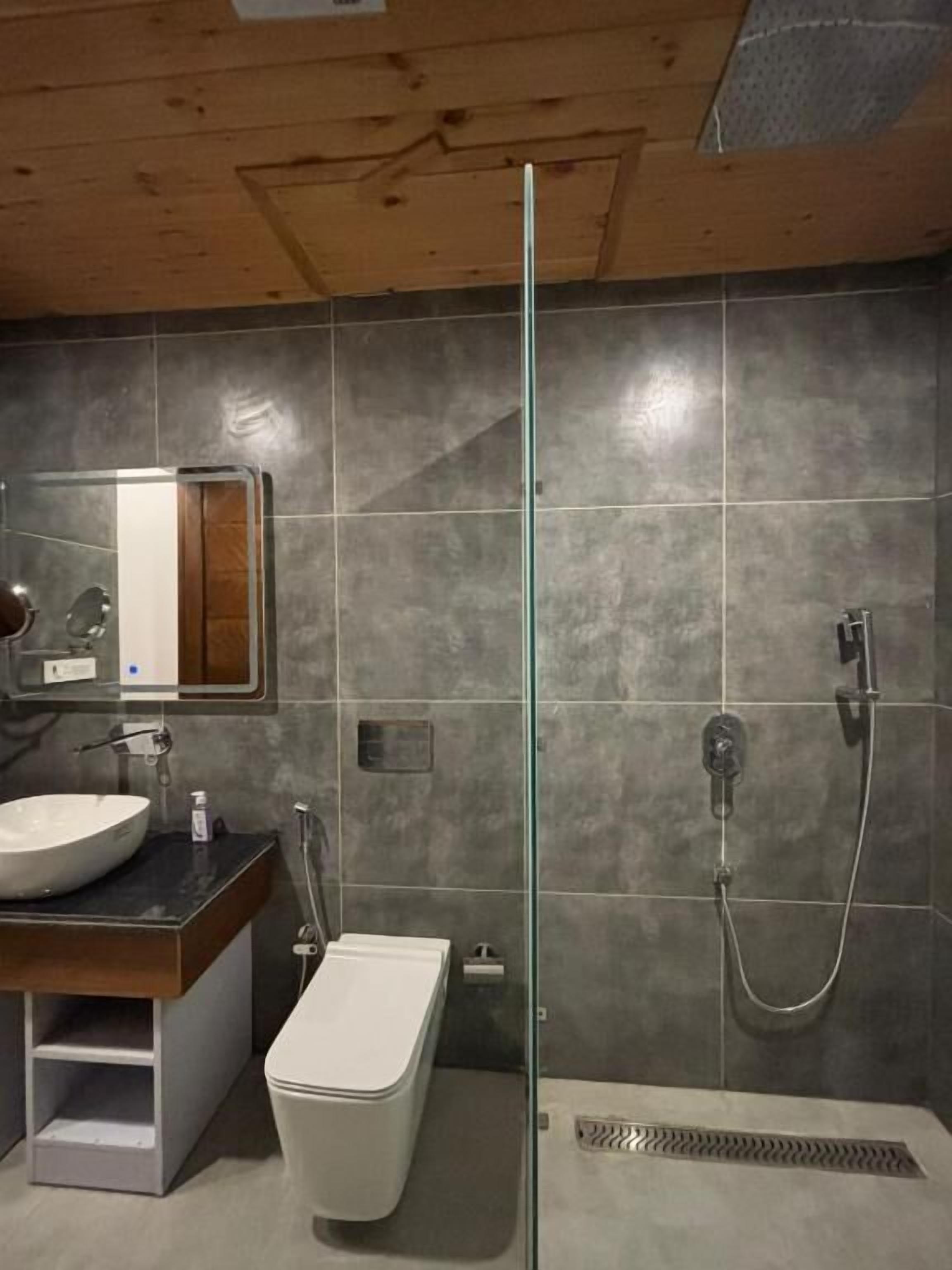 Ein Badezimmer mit Duschkabine aus Glas, Waschbecken mit Spiegel und Toilette.
