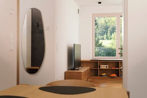 A modern interior with a large mirror, a flat-screen TV, and a view of a forest through a large window.