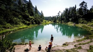 A group of people by a calm lake surrounded by dense forest and mountains. - NOOK - Nature Hideaway (Bad Aussee)