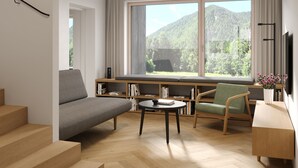 A modern living room with a sofa, chairs, a coffee table, and a bookshelf. There is a large window with a view of mountains. - NOOK - Nature Hideaway (Bad Aussee)