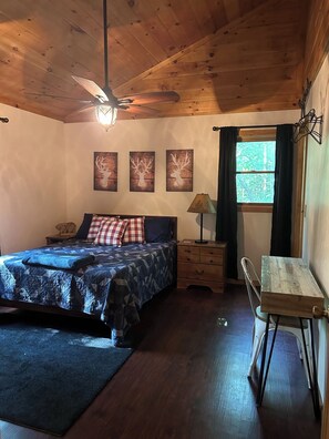 Ein Schlafzimmer mit Bett, Schreibtisch, Deckenventilator und drei Wandbildern von Hirschköpfen.