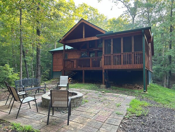 Eine Hütte mit einer Terrasse, Sitzgelegenheiten im Freien und einer Feuerstelle.