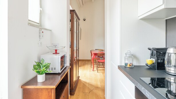 A kitchen with a microwave, coffee machine, and a dining area with chairs and a table. - The Gem of the Kalsa by Wonderful Italy (Palermo)