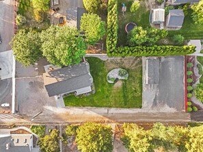 An aerial view of a residential area with a house, a swimming pool, and a well-maintained lawn.