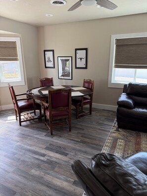 A dining area with a round table, four chairs, and a ceiling fan.