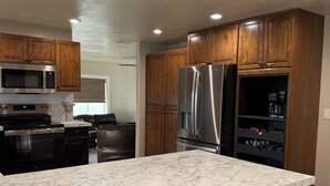 A modern kitchen with wooden cabinets, stainless steel appliances, and a marble countertop.