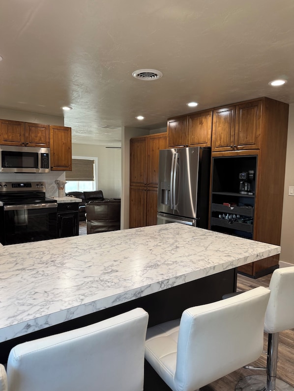 A modern kitchen with wooden cabinets, stainless steel appliances, and a marble countertop.