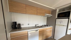 Una cocina compacta con gabinetes de madera, lavavajillas, cocina a gas y refrigerador.