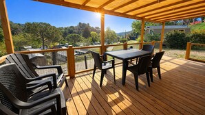 Una terraza techada al aire libre con una mesa y sillas, con vistas a un paisaje pintoresco.