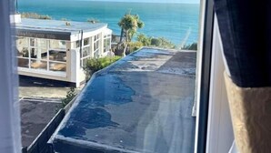 A view of the ocean from a window overlooking a building with a flat roof and a clear sky. - The Carlton Hotel (Shanklin)