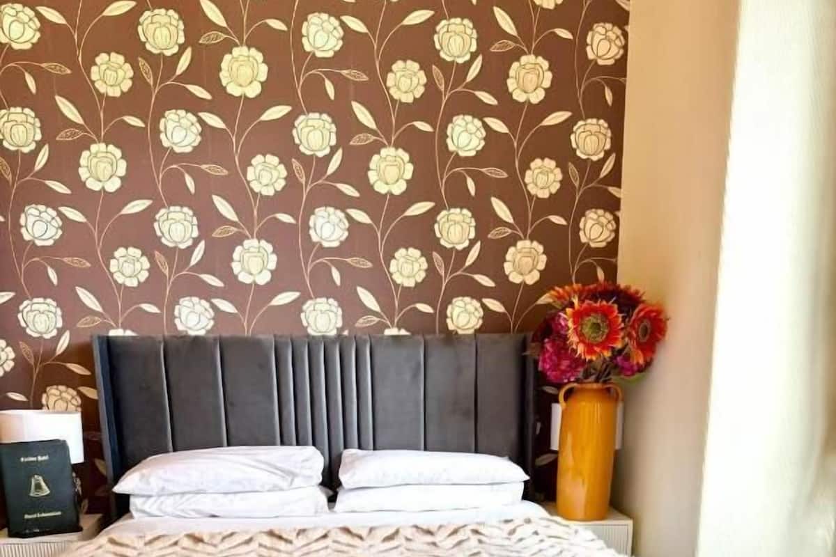 A bed with a black headboard, white pillows, and a patterned bedspread.