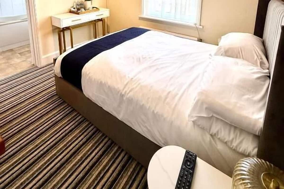 A hotel room with a bed, a desk, a television, and a window.