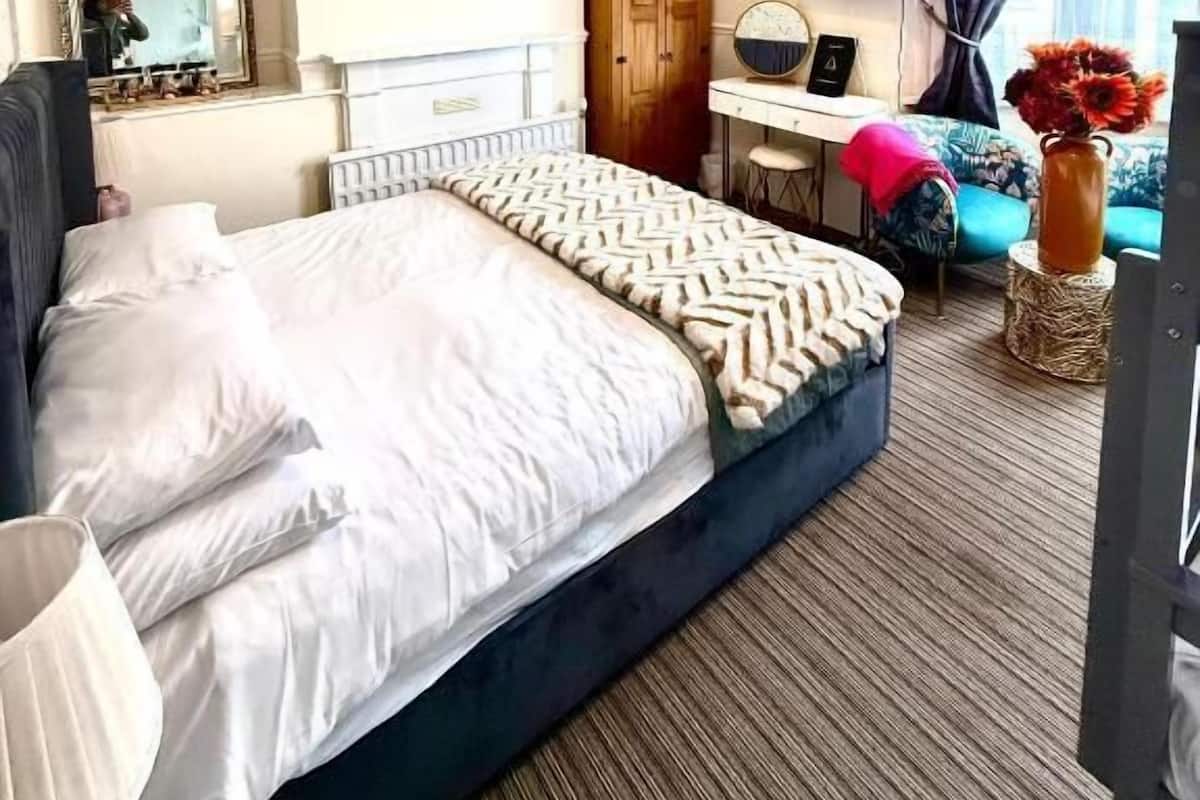 A hotel room with a bed, a desk, a chair, a television, and a window with curtains.