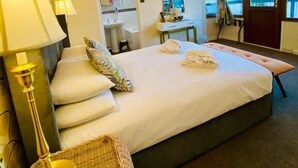 A hotel room with a bed, bedside lamps, a mirror, a small table, and a view of the sea through large windows. - The Carlton Hotel (Shanklin)
