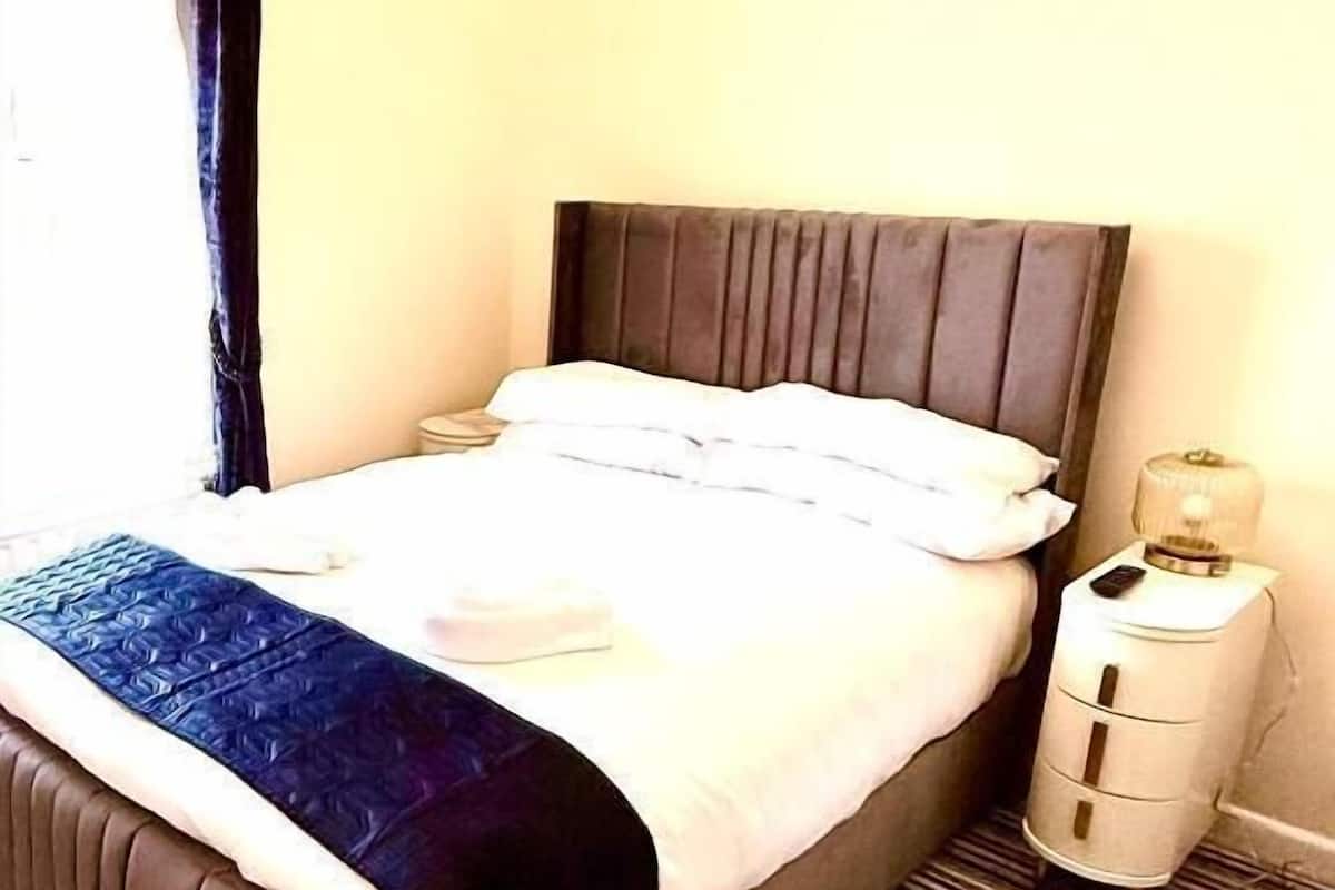 A hotel room with a bed, a nightstand, a lamp, and a striped carpet.