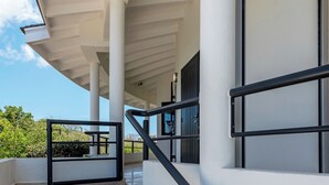 A staircase leading to a covered area with a railing, a door, and a view of greenery. - Villa Luna Del Sol l Unique Oceanview l Coral Estate Resort (Sint Willibrordus)