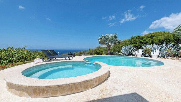 A pool area with two separate pools, lounge chairs, and a view of the ocean. - Villa Luna Del Sol l Unique Oceanview l Coral Estate Resort (Sint Willibrordus)